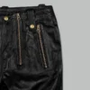 Black leather pants with zippers close-up of gold zipper hardware and leather texture on left side