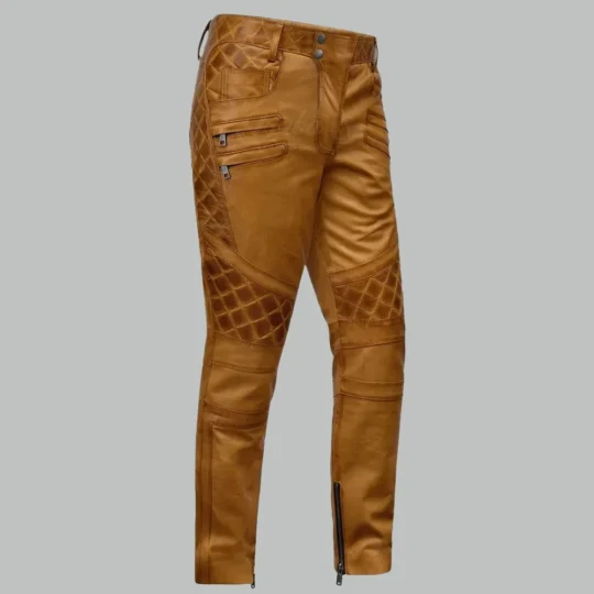 Burnt orange leather pants for men, side view, with quilted thigh and knee panels, zipper pockets and ankle zippers