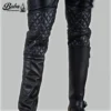 Close-up of diamond-stitched quilted knee panels on mens black leather pants, worn with engineer boots