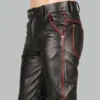 Close-up of mens black leather jeans showing red piping on the front pocket, back pocket, and side seam, with metal rivets and belt loops